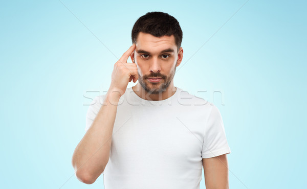 man with finger at temple over blue background Stock photo © dolgachov