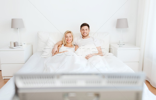 счастливым пару кровать домой смотрят телевизор Сток-фото © dolgachov