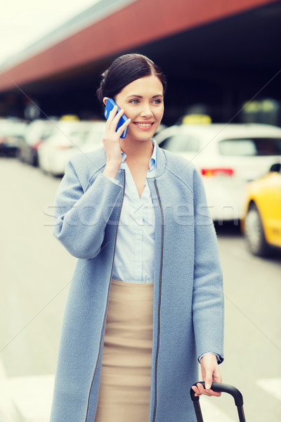 smiling woman with smartphone over taxi in city Stock photo © dolgachov