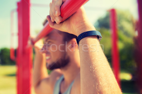 young man exercising on horizontal bar outdoors Stock photo © dolgachov