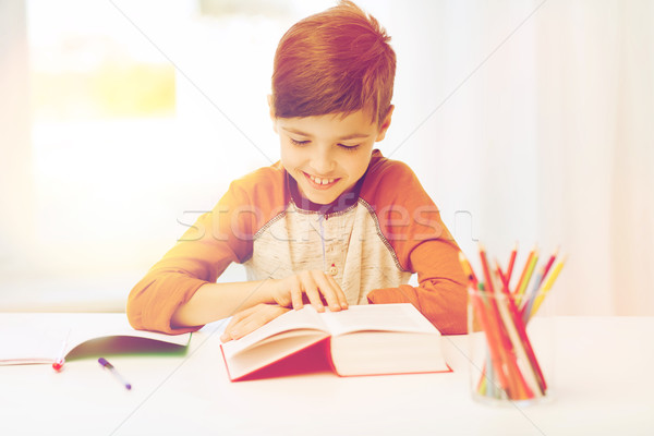 Foto stock: Sorridente · estudante · menino · leitura · livro · casa