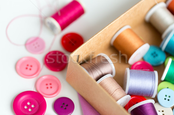 Stock photo: box with thread spools and sewing buttons on table