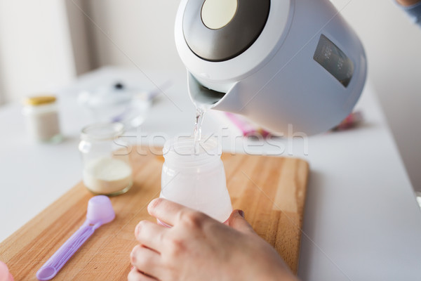 hands with kettle and bottle making baby milk Stock photo © dolgachov