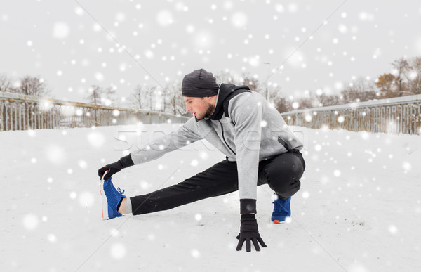 man exercising and stretching leg on winter bridge Stock photo © dolgachov