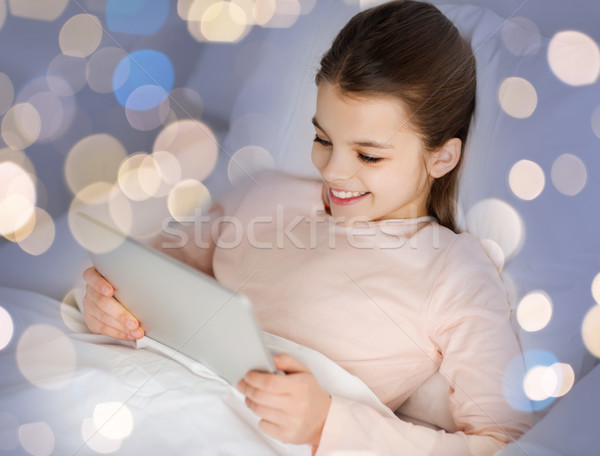 happy girl in bed with tablet pc over lights Stock photo © dolgachov
