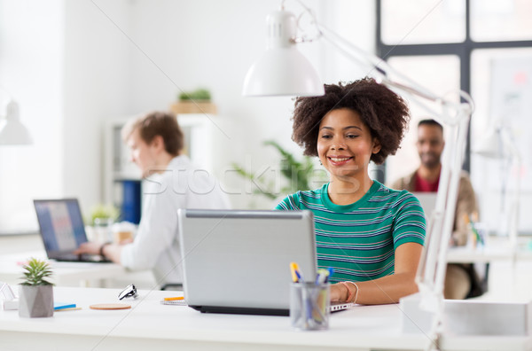 happy african woman with laptop computer at office Stock photo © dolgachov