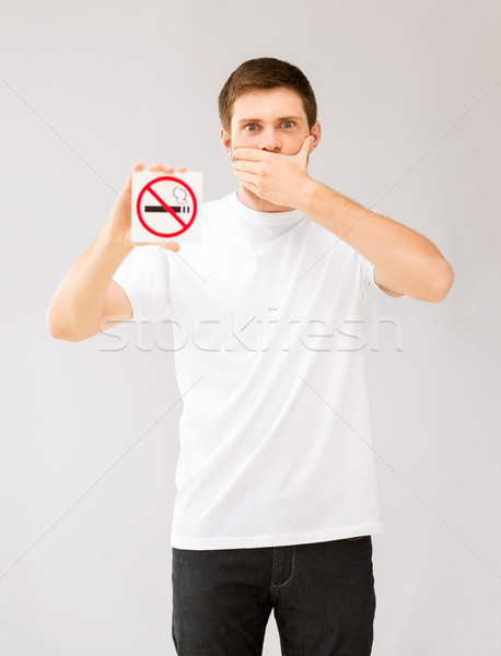 Fiatalember tart dohányozni tilos felirat kép férfi Stock fotó © dolgachov