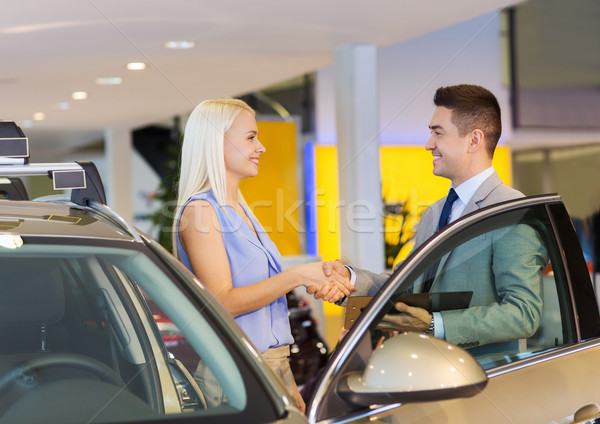 Stock photo: happy woman with car dealer in auto show or salon