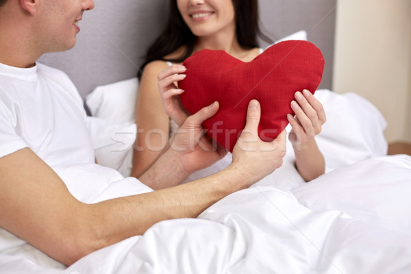Sorridente casal cama vermelho forma de coração travesseiro Foto stock © dolgachov