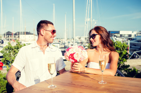 smiling couple with bunch and champagne at cafe Stock photo © dolgachov