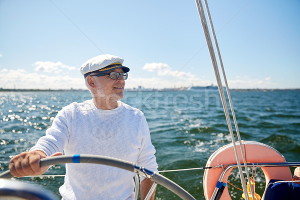 senior man at helm on boat or yacht sailing in sea Stock photo © dolgachov