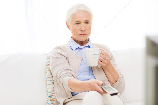 senior woman watching tv and drinking tea at home Stock photo © dolgachov