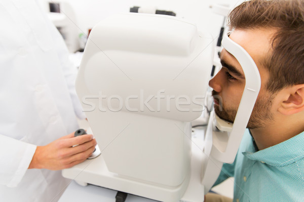 optician with autorefractor and patient at clinic Stock photo © dolgachov