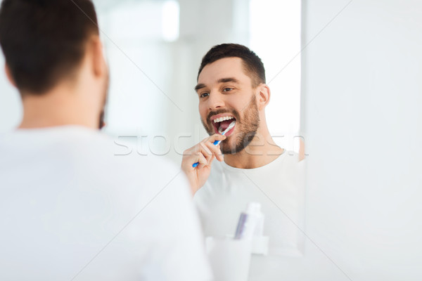 Homem escova de dentes limpeza dentes banheiro Foto stock © dolgachov