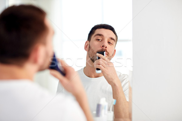 man shaving mustache with trimmer at bathroom Stock photo © dolgachov