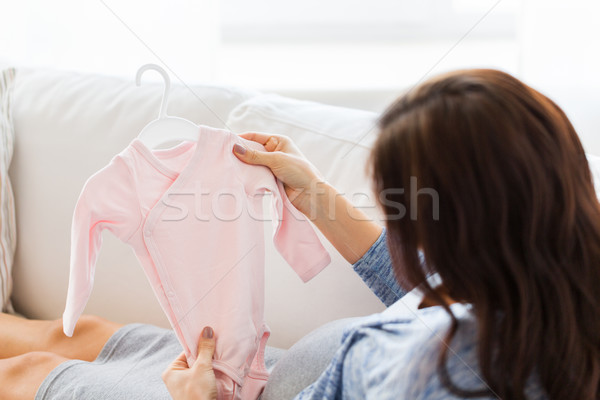 close up of happy woman with baby bodysuit at home Stock photo © dolgachov