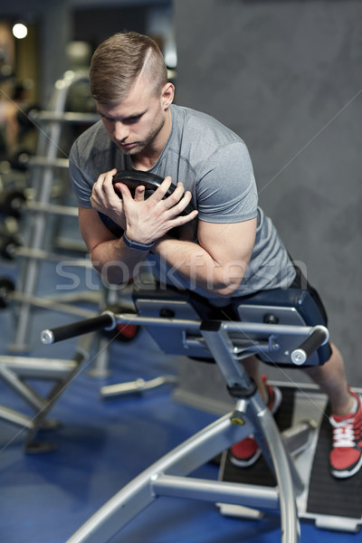 young man flexing back muscles on bench in gym Stock photo © dolgachov