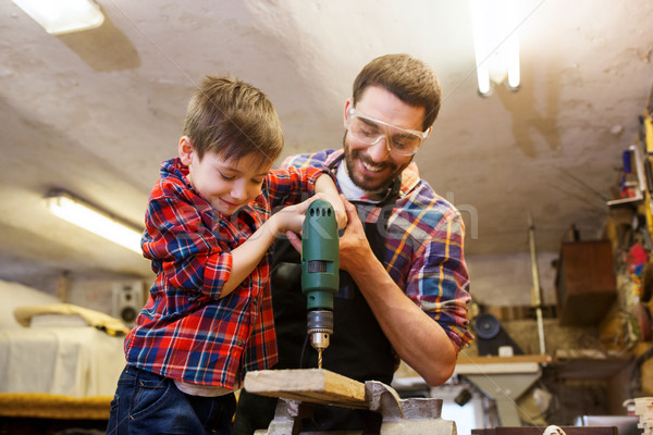 father and son with drill working at workshop Stock photo © dolgachov