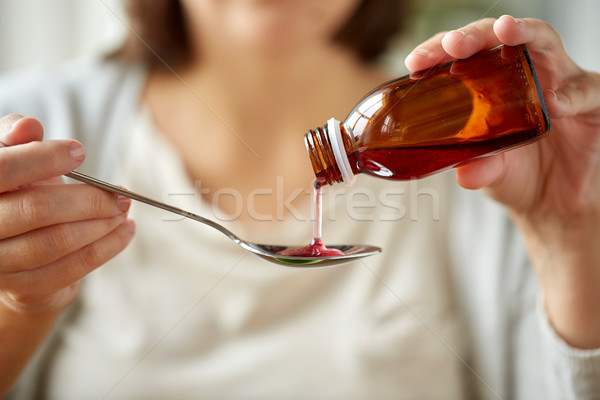 woman pouring medication from bottle to spoon Stock photo © dolgachov