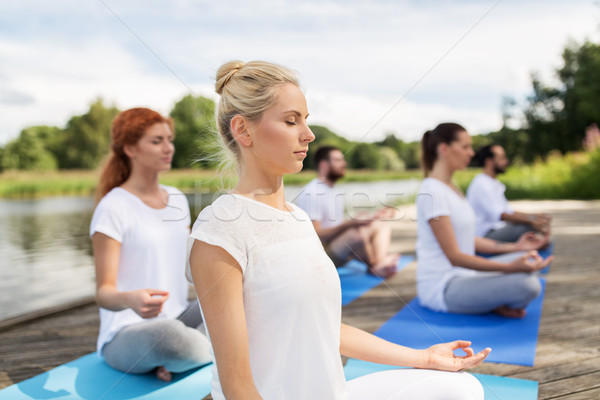 people meditating in yoga lotus pose outdoors Stock photo © dolgachov