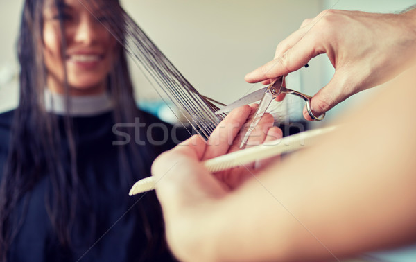 Stock photo: happy woman with stylist cutting hair at salon