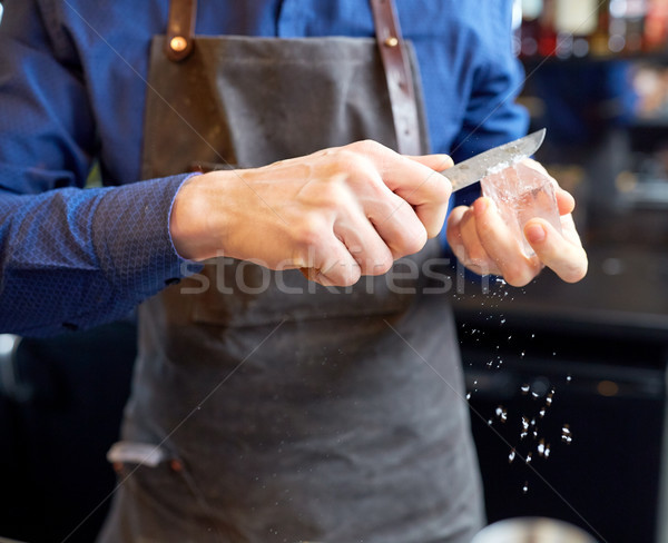 Stock photo: bartender grinding ice cube with knife at bar