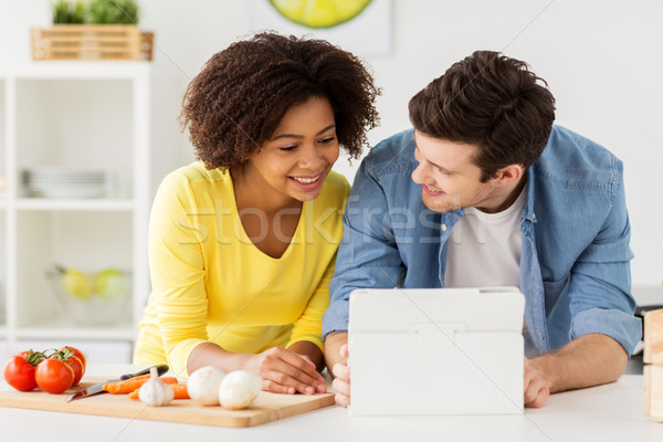 Stock photo: happy couple with tablet pc cooking food at home