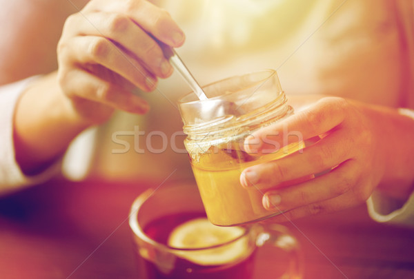 close up of woman adding honey to tea with lemon Stock photo © dolgachov