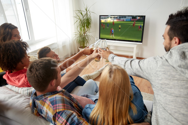 friends clinking beer and watching soccer game Stock photo © dolgachov