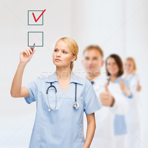 doctor or nurse drawning checkmark into checkbox Stock photo © dolgachov