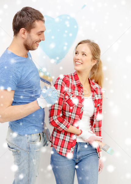smiling couple painting small heart on wall Stock photo © dolgachov