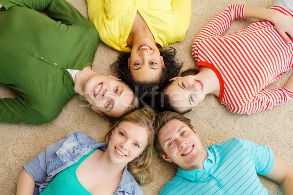 group of smiling people lying down on floor Stock photo © dolgachov