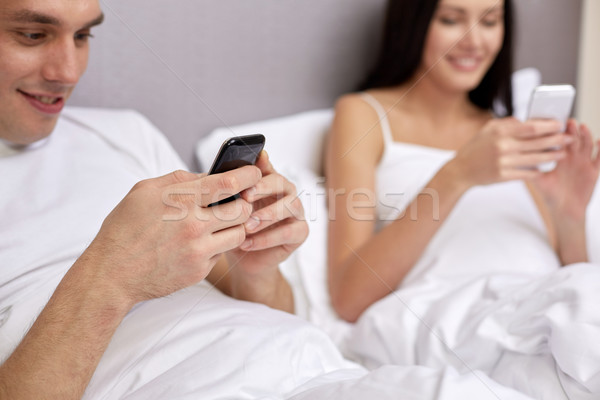 Foto stock: Sonriendo · Pareja · cama · smartphones · personas