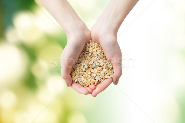 Stock photo: close up of woman hands holding oatmeal flakes