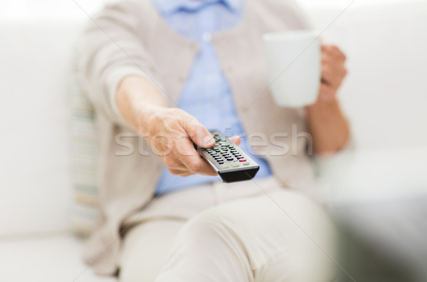 Stock photo: senior woman watching tv and drinking tea at home