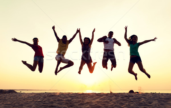 smiling friends dancing and jumping on beach Stock photo © dolgachov