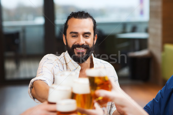man clinking beer glass with friends at restaurant Stock photo © dolgachov