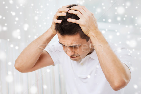 Stock photo: unhappy man suffering from head ache at home