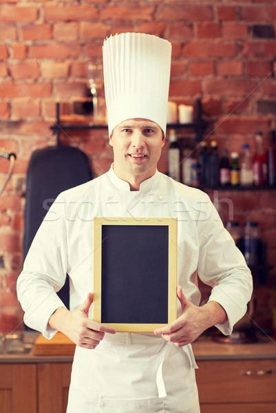 happy male chef with blank menu board in kitchen Stock photo © dolgachov