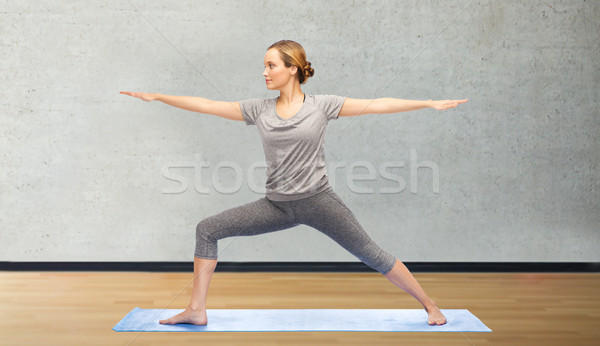 woman making yoga warrior pose on mat Stock photo © dolgachov