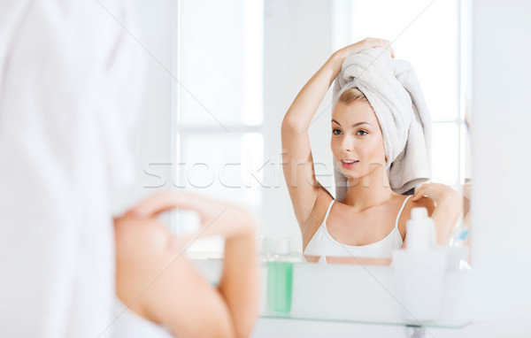 happy young woman with towel at mirror in bathroom Stock photo © dolgachov