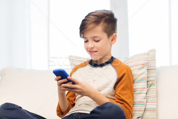 boy with smartphone texting or playing at home Stock photo © dolgachov