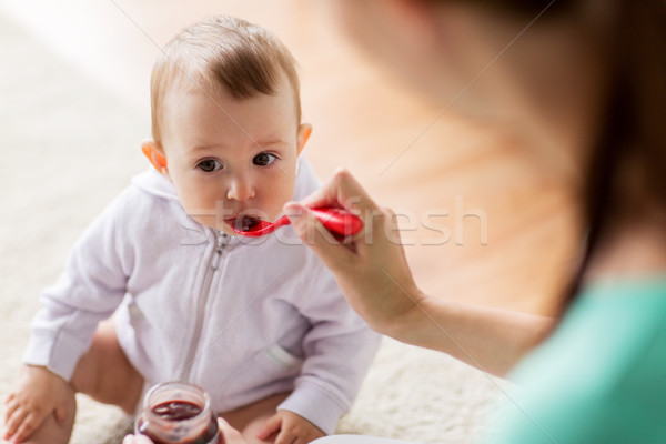 mother with spoon feeding little baby at home Stock photo © dolgachov