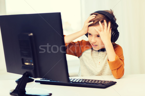 Stock photo: terrified boy with computer and headphones at home