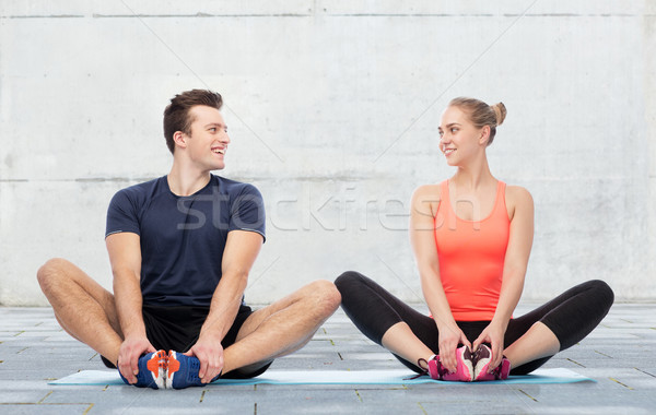 happy sportive man and woman sitting on mats Stock photo © dolgachov