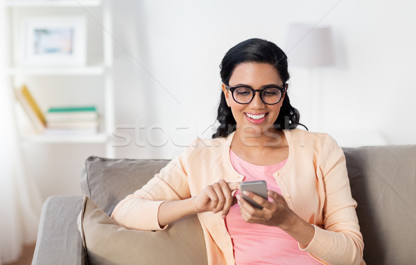 Stock photo: happy woman texting message on smartphone at home