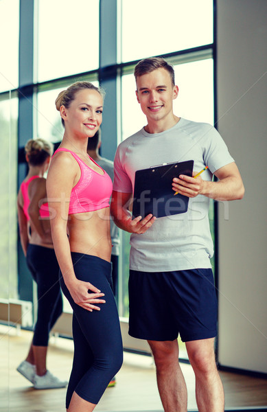 smiling young woman with personal trainer in gym Stock photo © dolgachov
