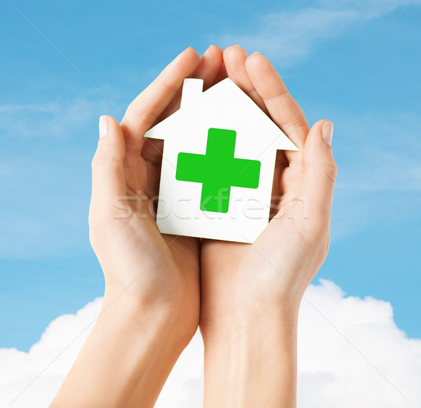 hands holding paper house with green cross Stock photo © dolgachov