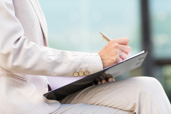 close up of business woman writing to clipboard Stock photo © dolgachov