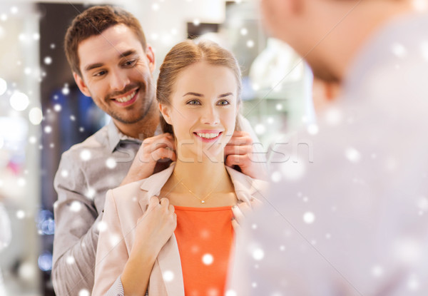 couple trying golden pendant on at jewelry store Stock photo © dolgachov